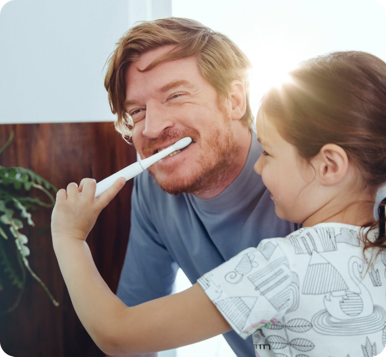 A man and a young girl happily brushing their teeth together