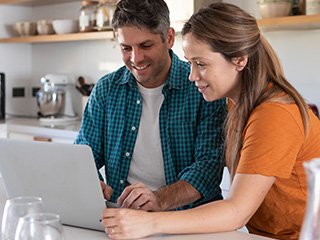 Couple smiling while looking at laptop