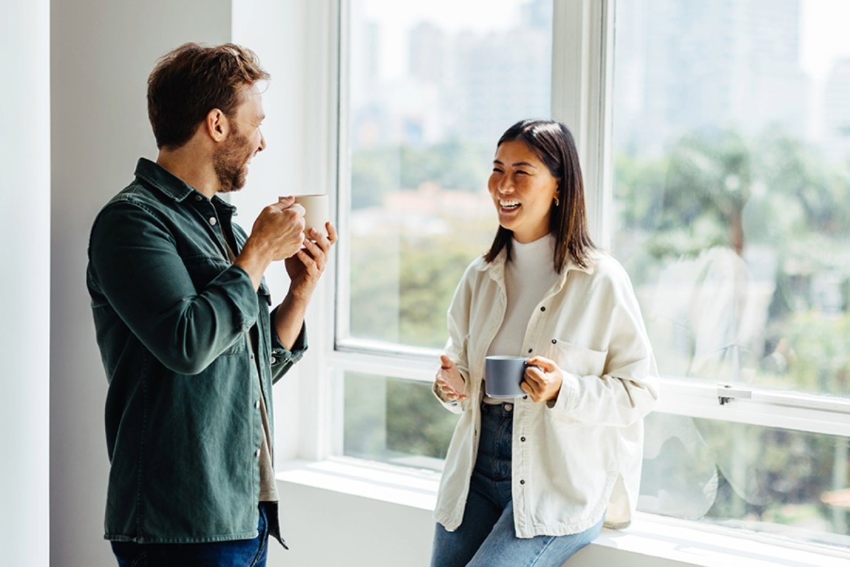 A man and woman sit in an office, enjoying coffee together while engaged in conversation.