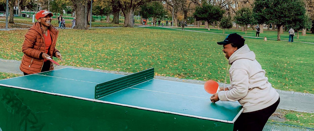 Two people playing ping pong on a green table.