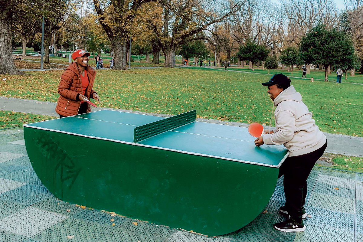 Two people playing ping pong on a green table.