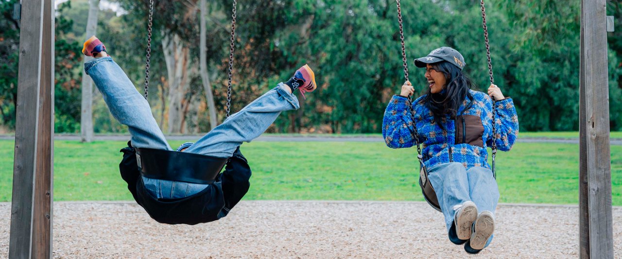 Two friends swinging together in a playground.