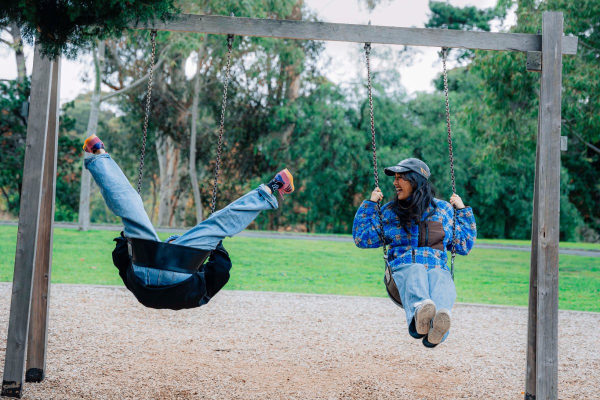 Two friends swinging together in a playground.