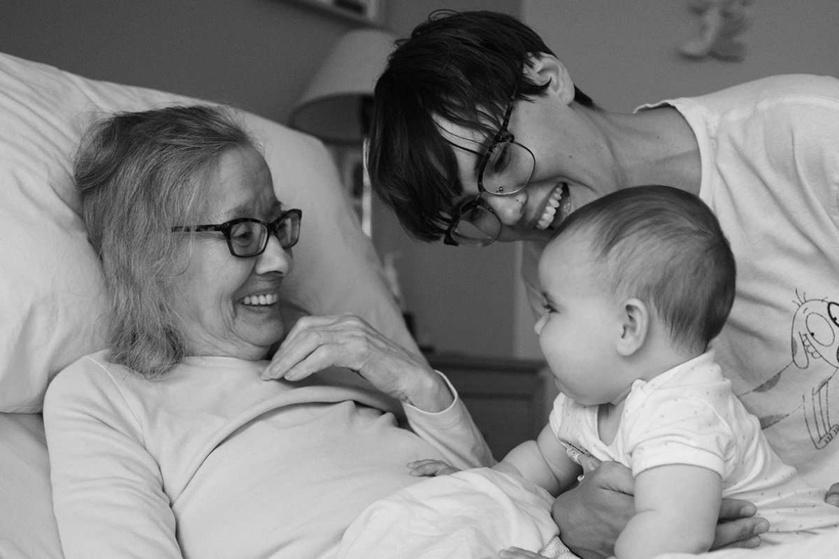 A young woman and an older woman happily holding a baby..