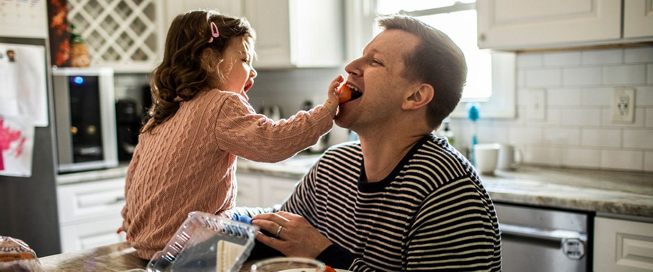 Young daughter playfully feeding dad