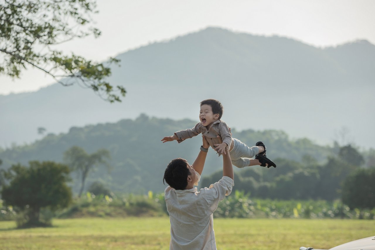 Asian young happy family enjoy vacation on beach in the evening. Dad, mom and kid relax playing together near sea when sunset while travel holiday. Lifestyle travel holiday vacation summer concept.