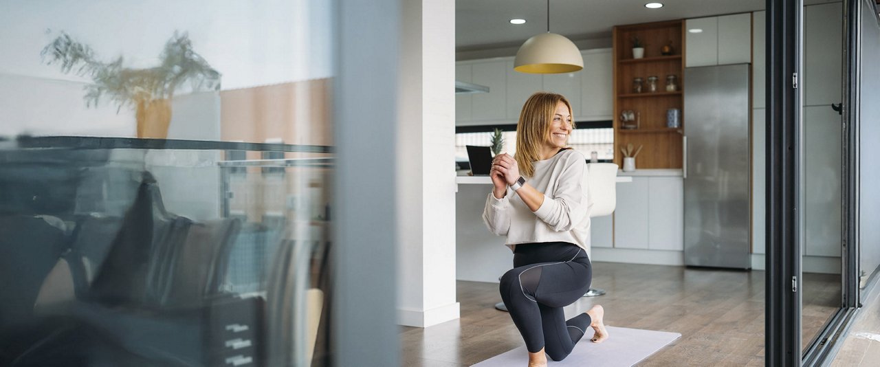 A woman performs a yoga pose in front of a glass door, highlighting her balance and concentration in a peaceful setting