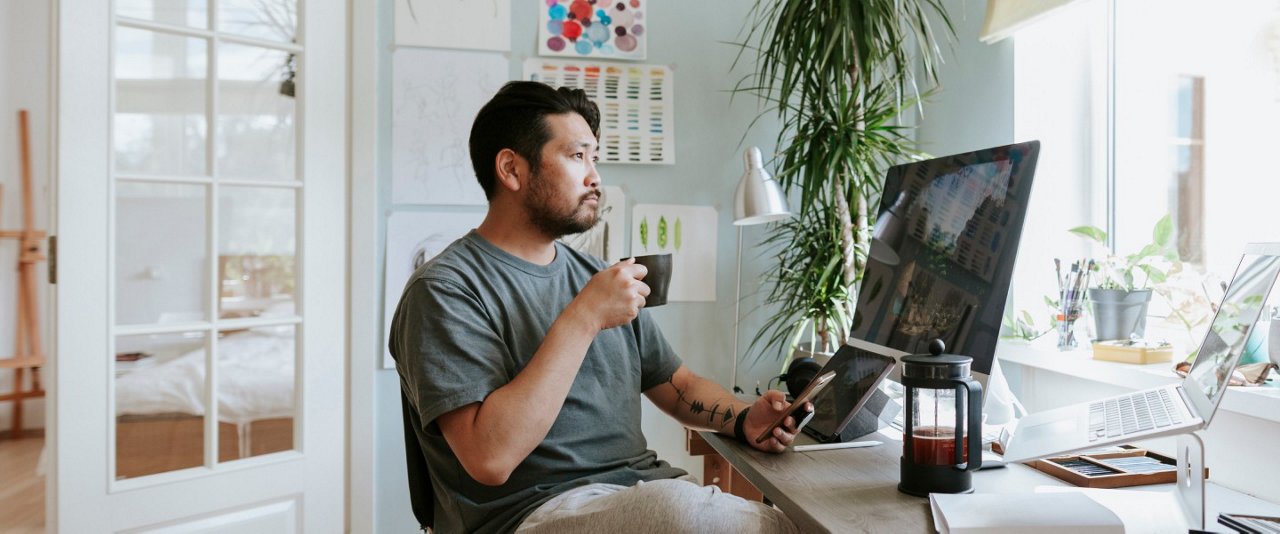 A man at a desk, sipping coffee, focused on his tasks or thoughts.