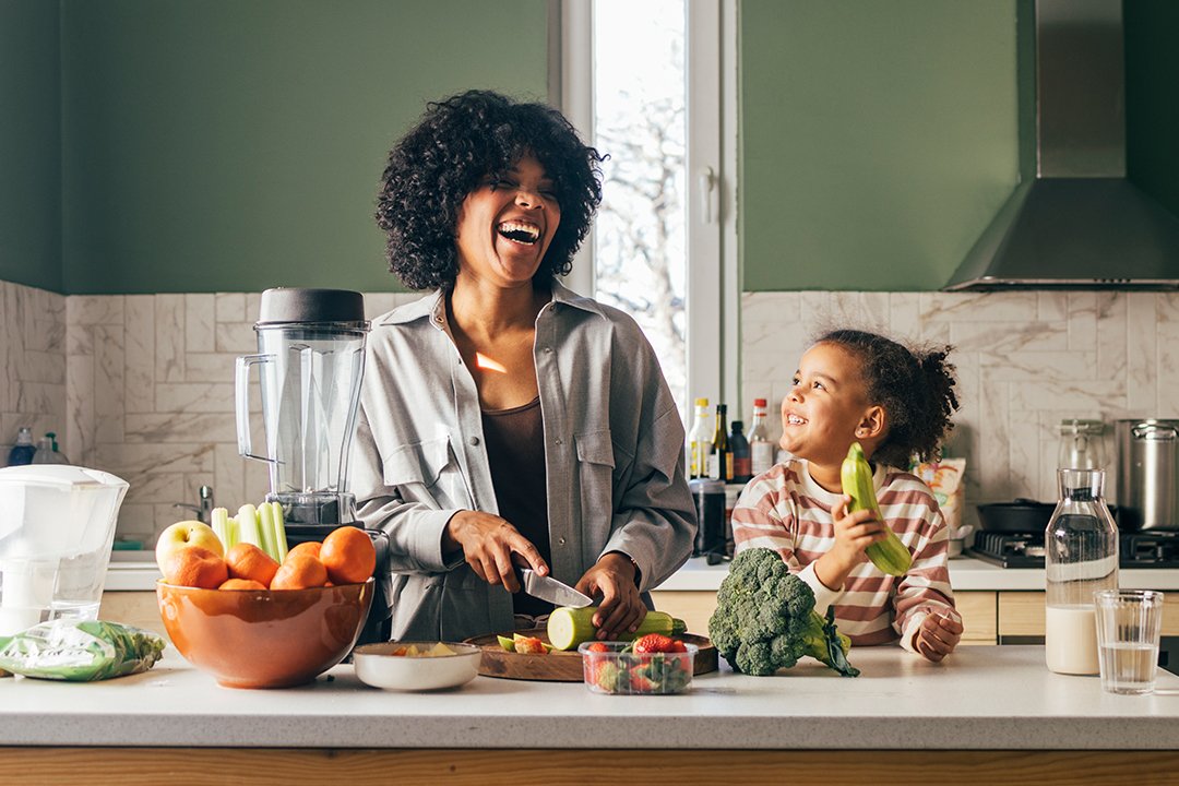 A woman and a child are engaged in cooking together in a bright, modern kitchen filled with various utensils and ingredients