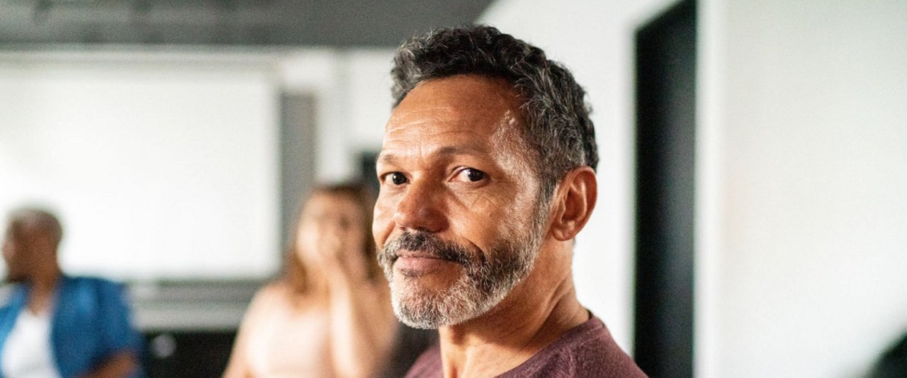 A bearded man with a mustache gazes directly at the camera, showcasing a friendly expression.