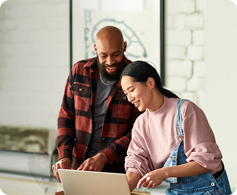 A man and woman sharing a moment, both looking intently at a laptop, possibly reviewing information together.