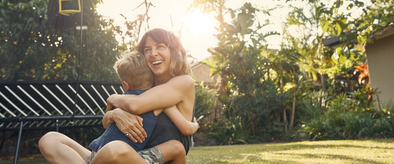 Mother hugging child in backyard