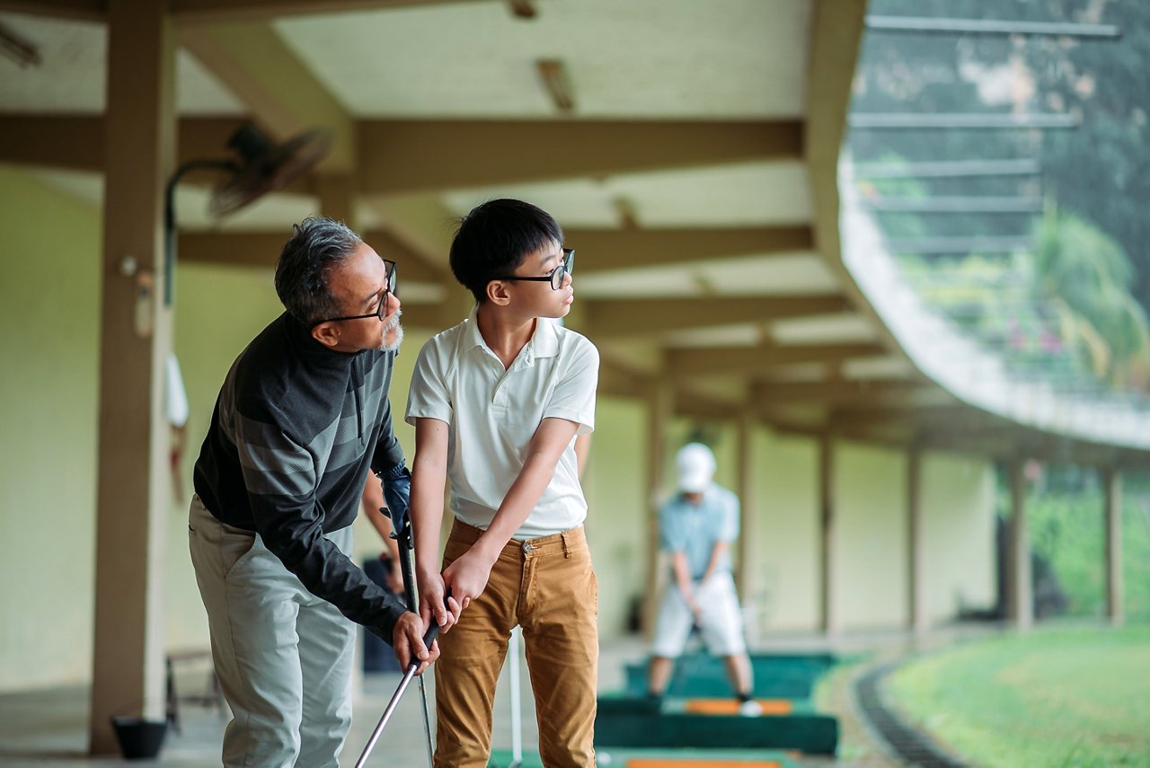 爺爺正在教導孫子練習打高爾夫球