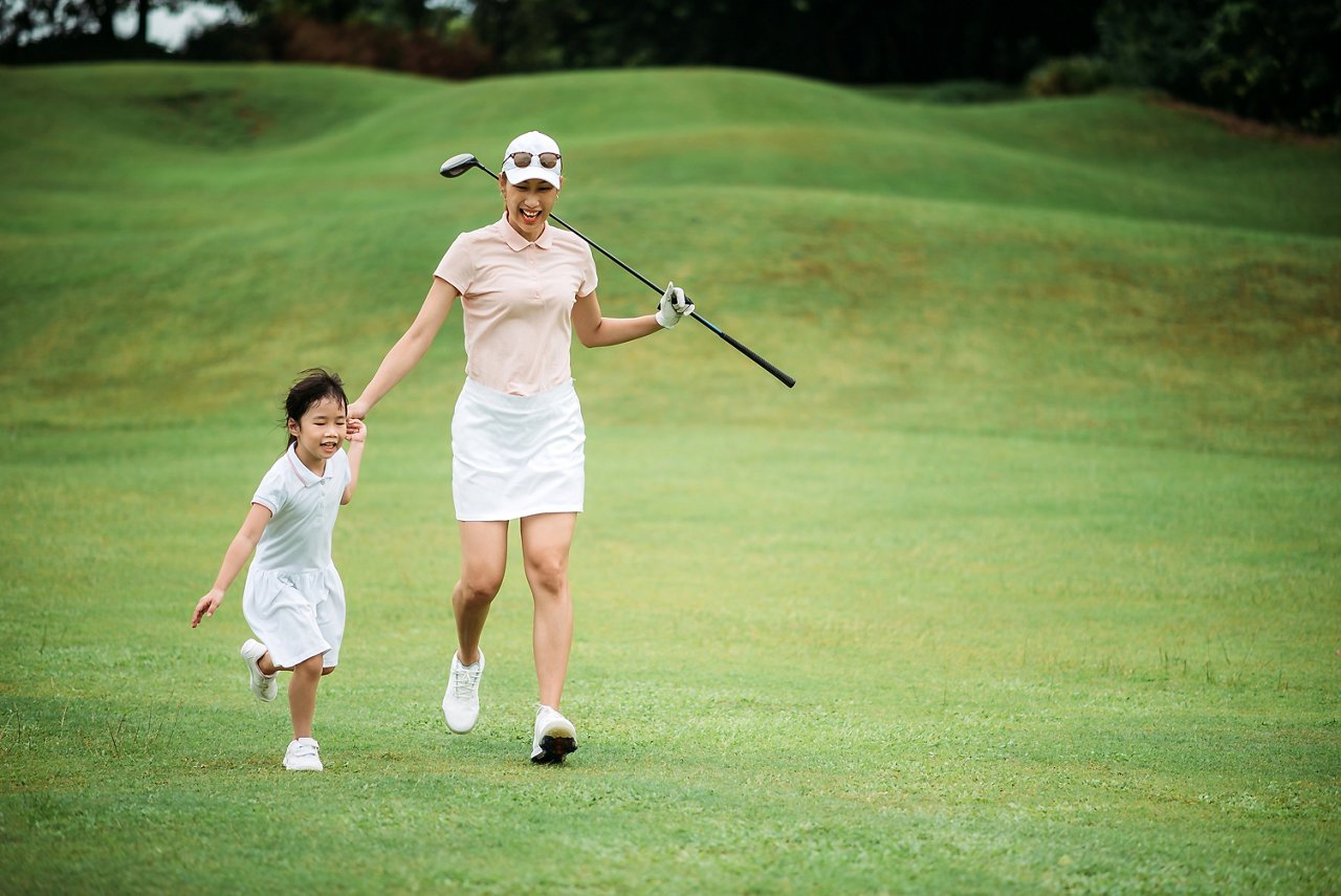 媽媽和女兒在高爾夫球場上開心地奔跑