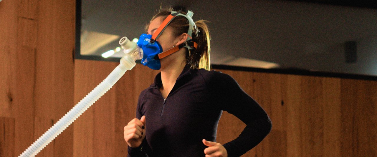 A woman in an exercise physiology lab, wearing a mask