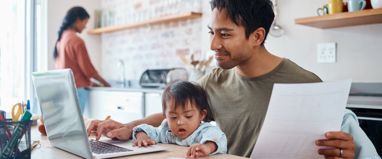 A man working the laptop with baby on his lap