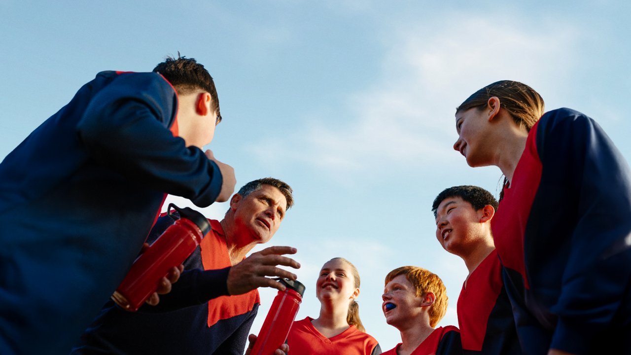 A group of young AFL players gathered around in a team huddle