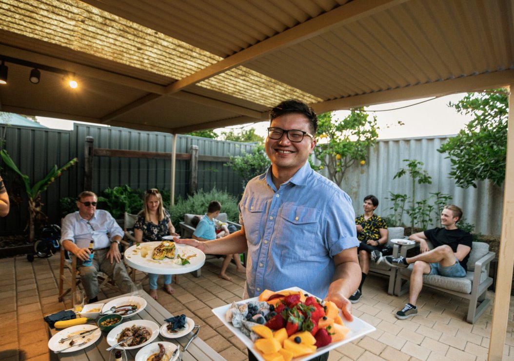 A man presents a plate of food to a group of people, showcasing a moment of sharing and enjoyment.