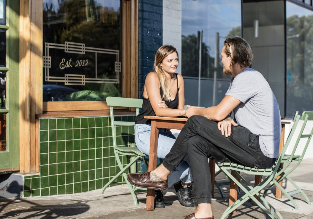 A man and woman enjoy a conversation while seated at a table outside a charming cafe.