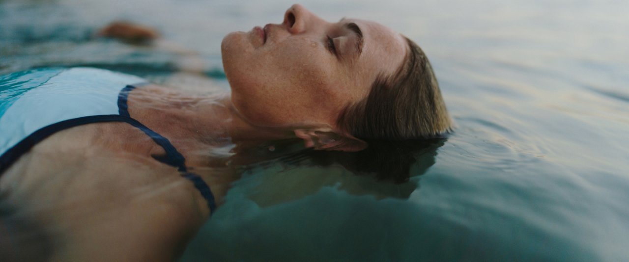 A serene woman floats peacefully in the water, her eyes gently closed