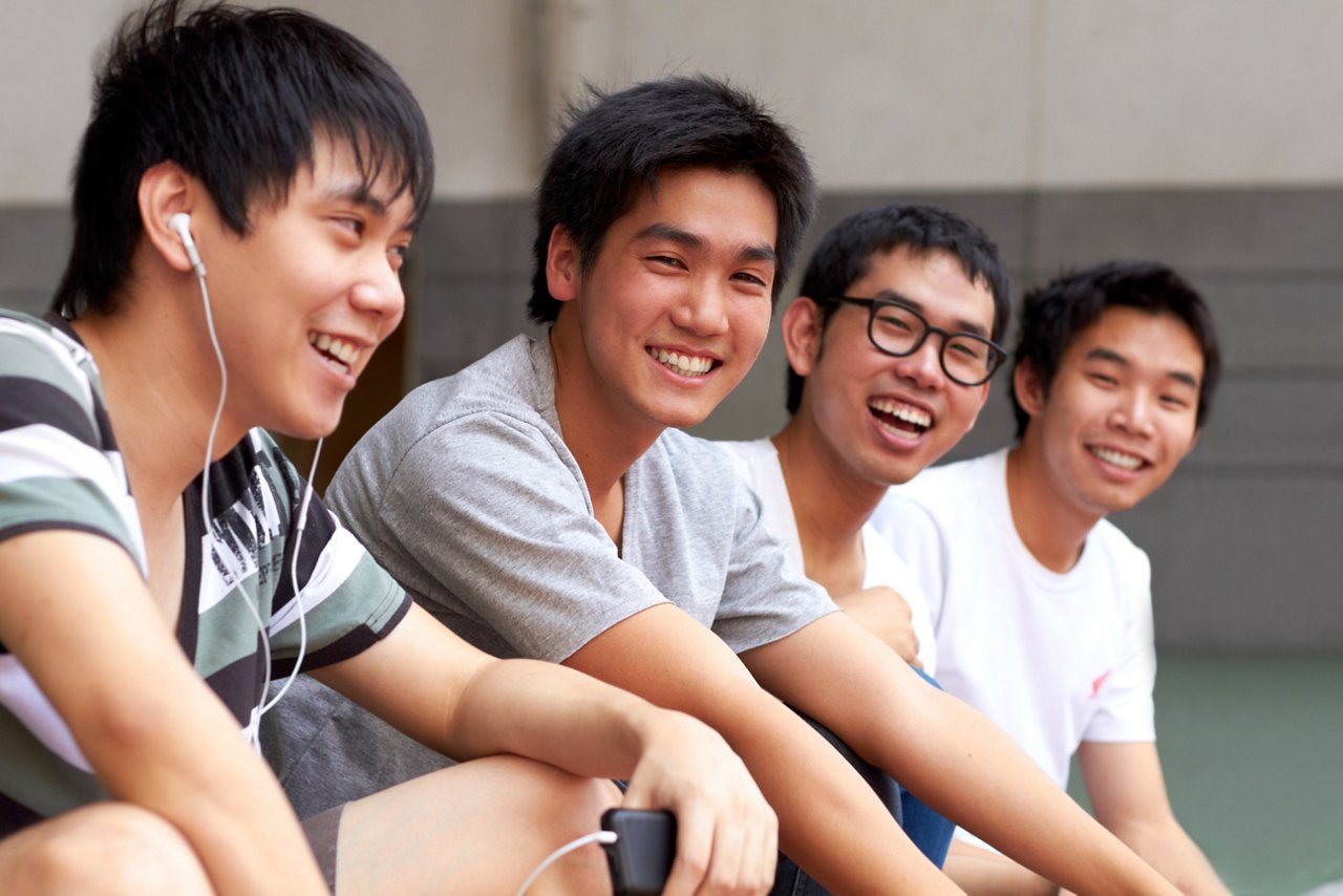 Group of four smiling Asian teenagers looking at the camera