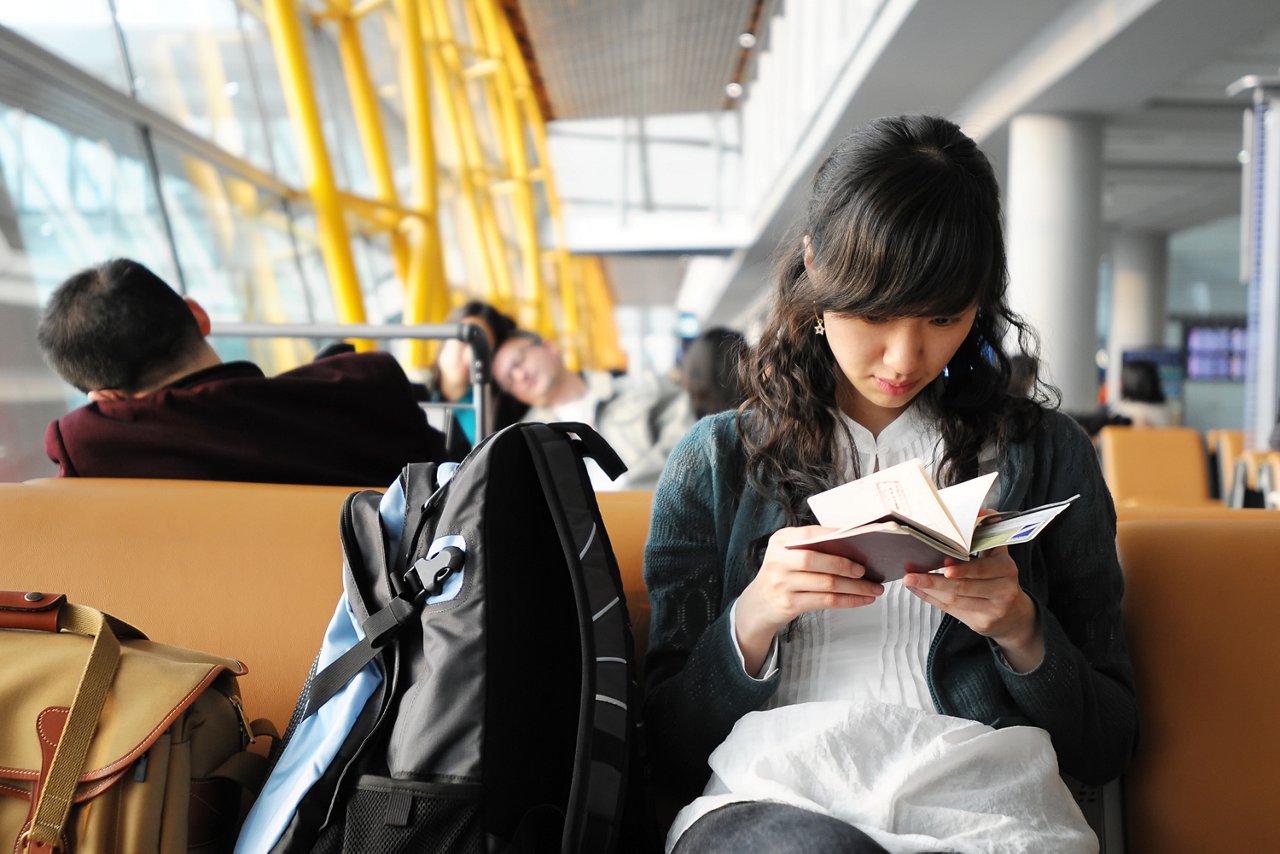 年輕亞洲女子在機場內看著自己的護照 