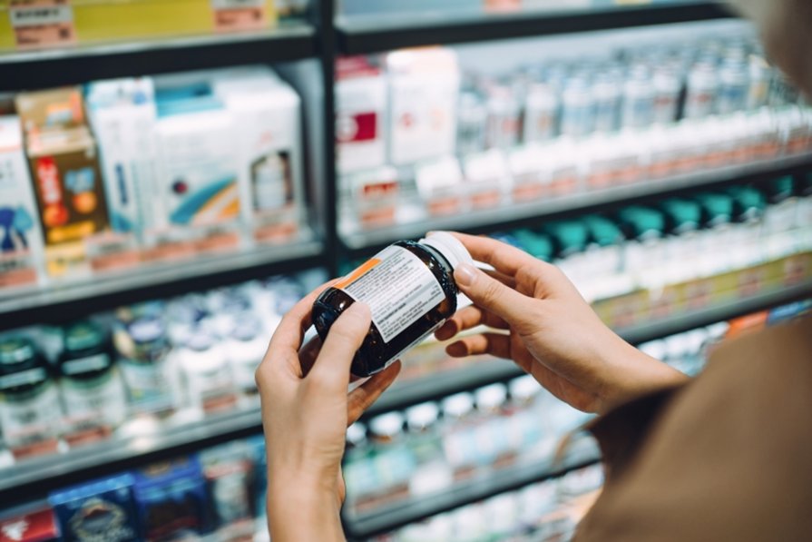 Woman looking at a bottle of medicine at a pharmacy