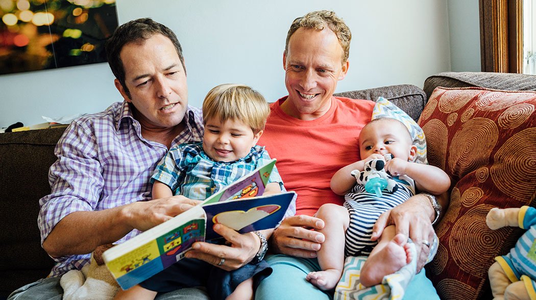 two men holding kids