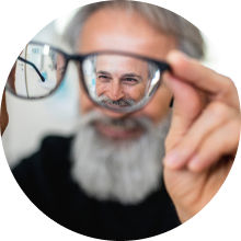 Man holding reading glasses and smiling