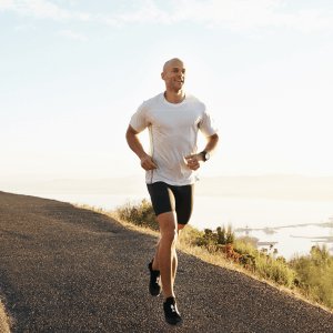 man jogging along coastal road, with the ocean and sky behind him