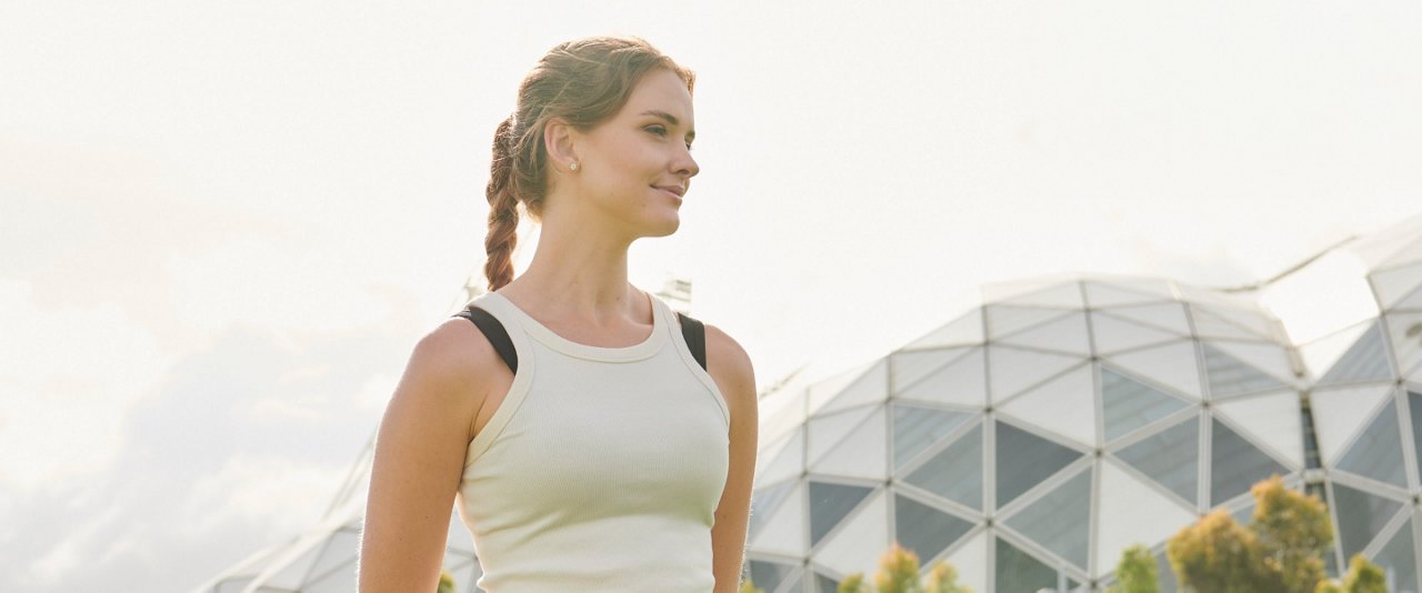 A woman in gym attire stands, looking calm and relaxed.