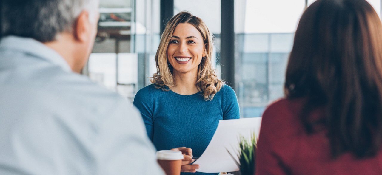Lady at desk with two customers (male and female)