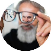 Man holding reading glasses and smiling