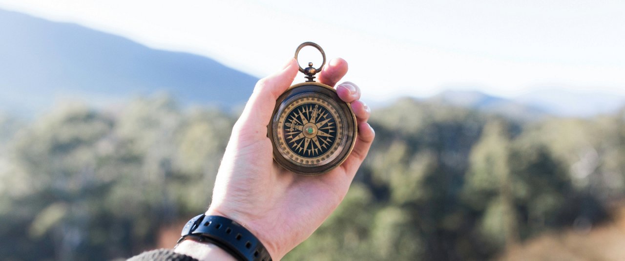 A person grasping a compass in their hand, symbolizing navigation and exploration.