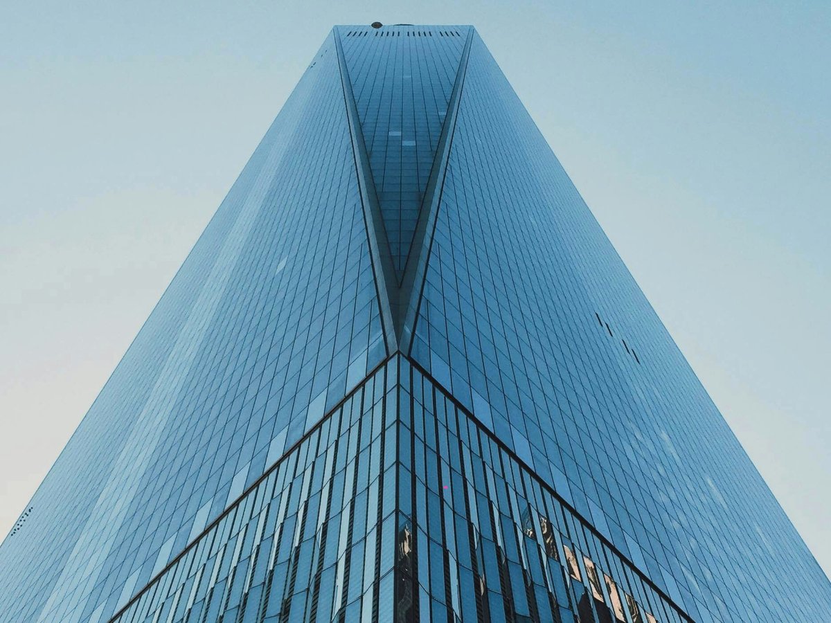 A tall building featuring a sleek glass facade reflecting the surrounding environment.