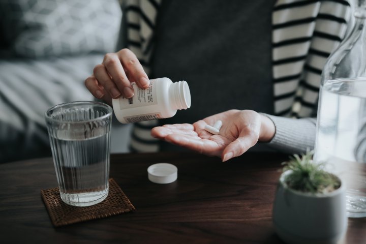 Woman taking probiotic supplements to promote gut health, digestive wellness, and immune system support.