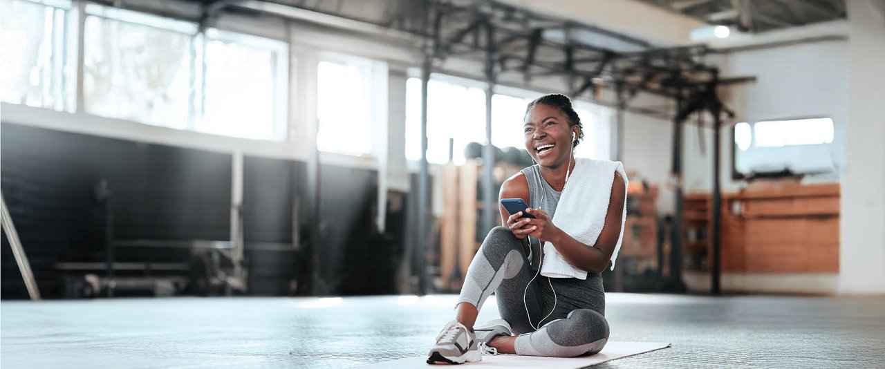 A woman on the floor, looking at her phone, dressed casually, with a serene atmosphere around her