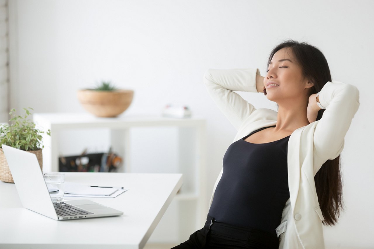 Young woman stretches at her work desk