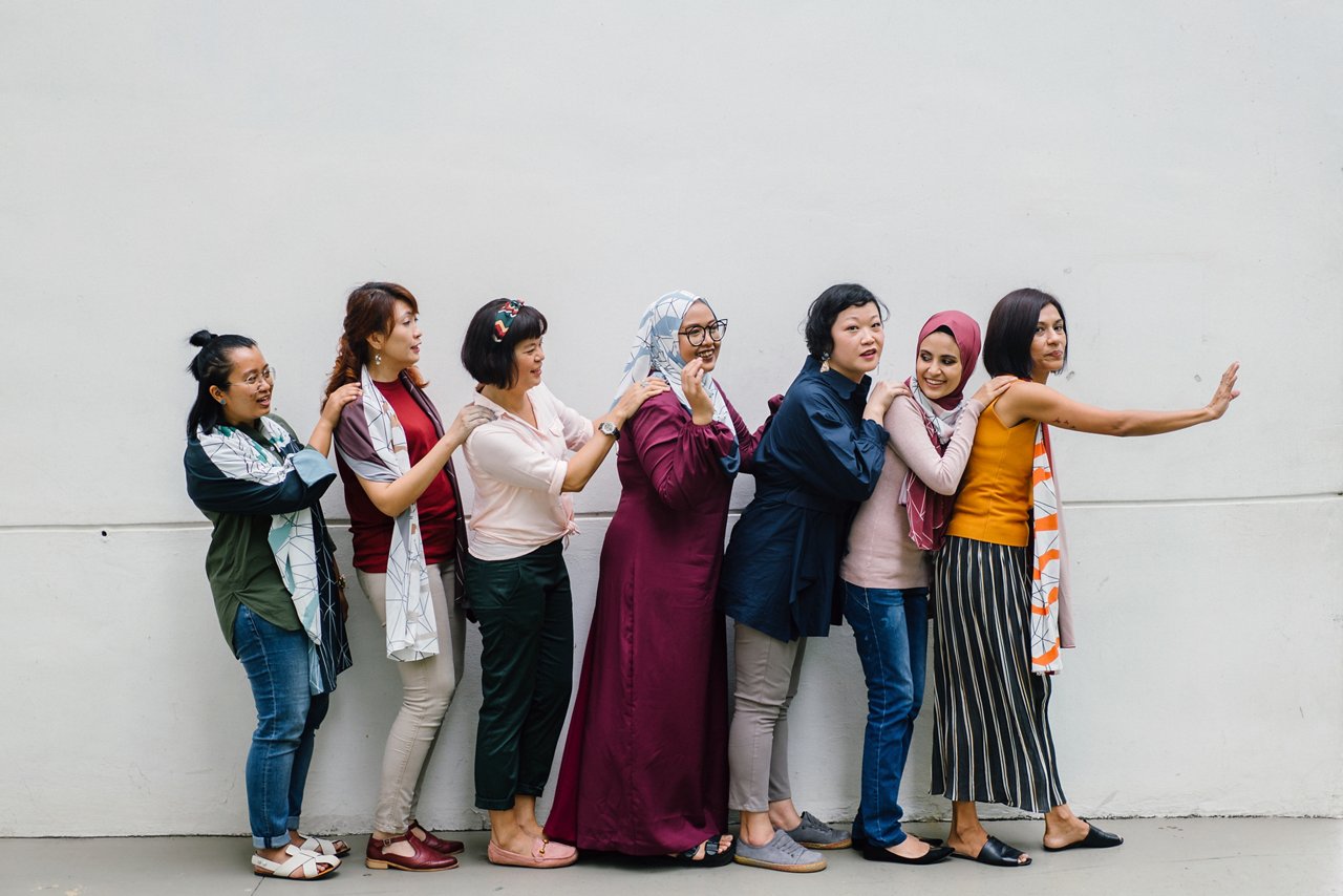 Diverse group of Asian women in a row smiling at one another.