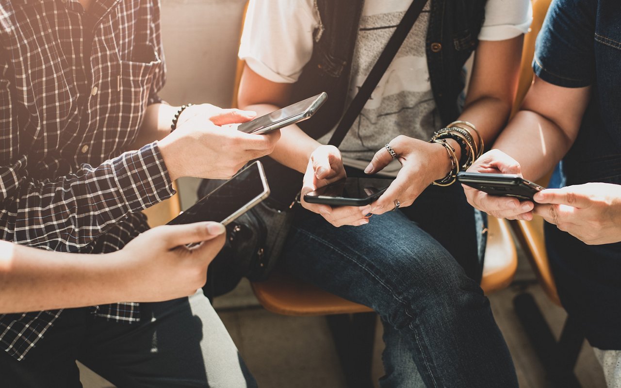A group of people holding smartphones gather together.