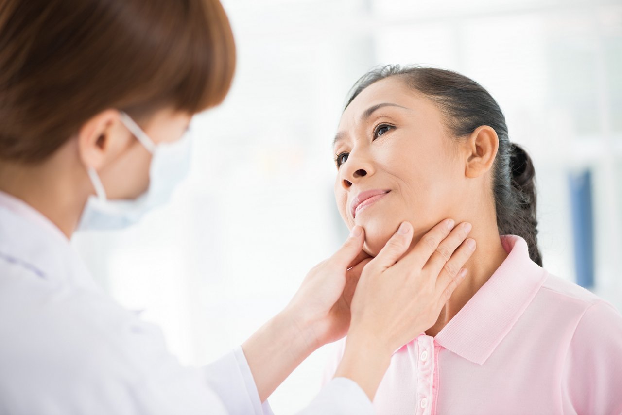 A doctor examines the throat area of a female patient.