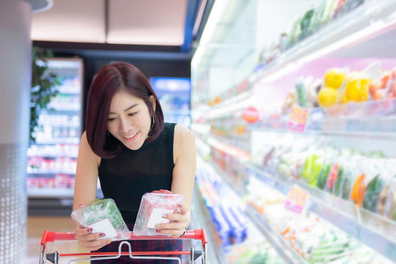 An Asian woman reading food ingredient label in a grocery store