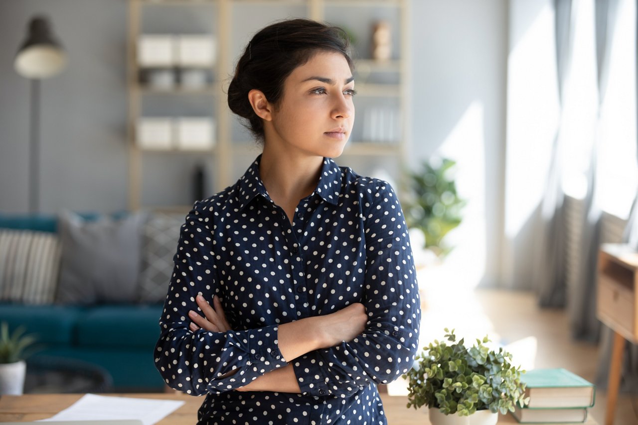 Young woman with her arms crossed looks away from camera.