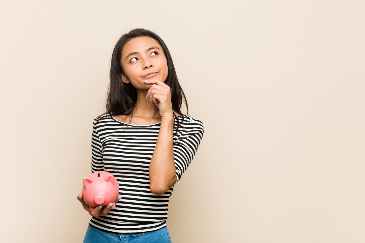 Young Asian woman holds a piggy bank.
