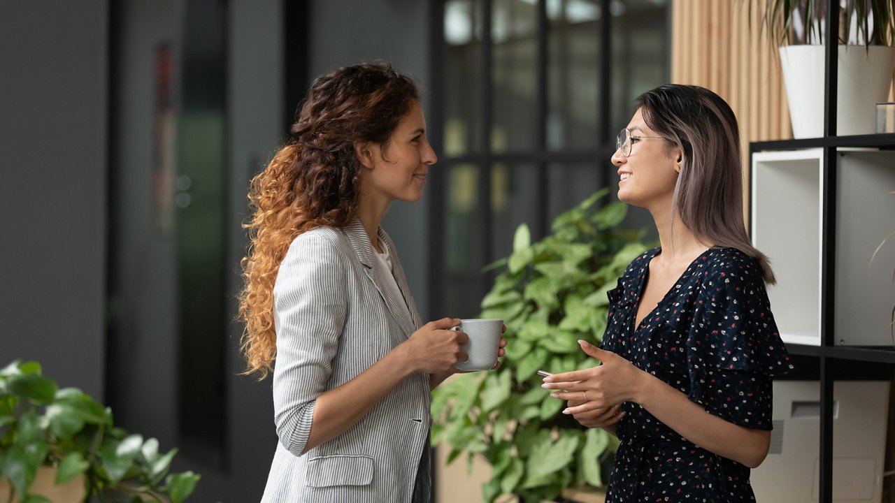 Two young women chat in the office hallway