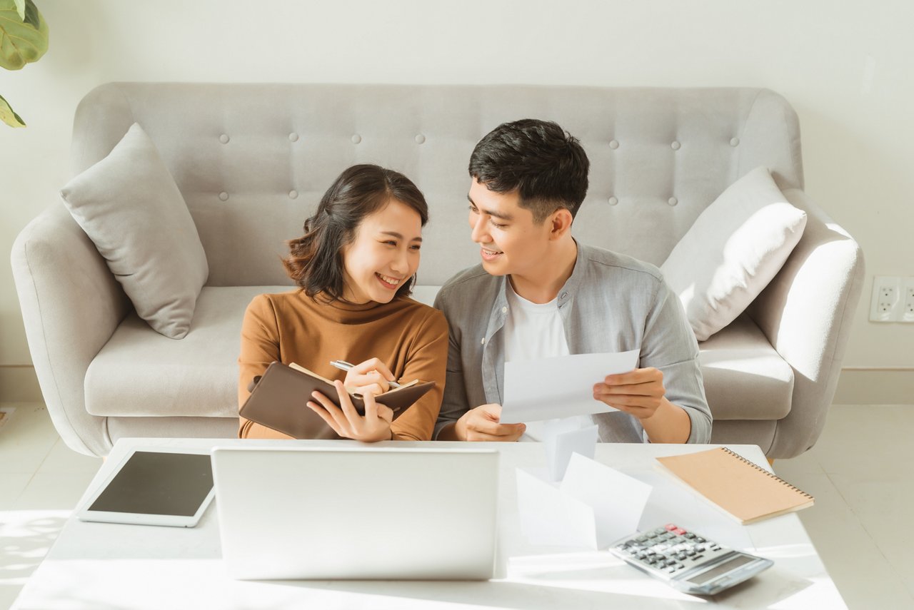 Young Asian couple looks through financial documents in the living room.