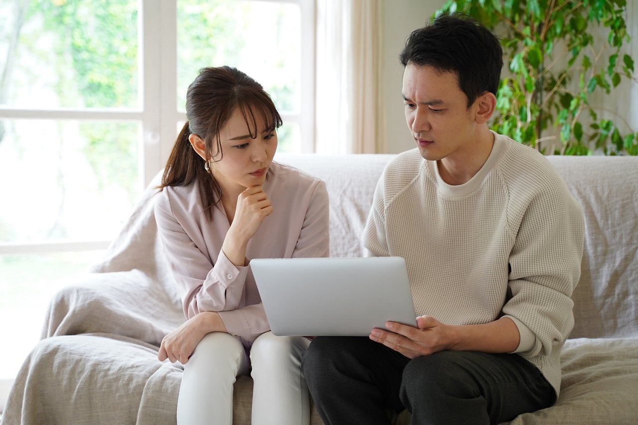 Young pensive couple stares at a laptop.