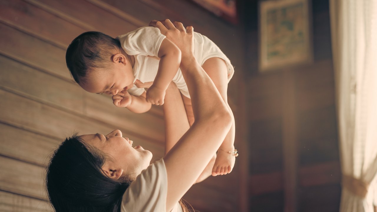 Mom plays and lifts her baby.