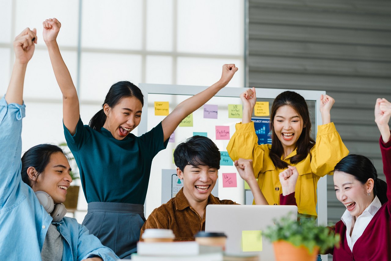 Group of young and diverse people cheer at work