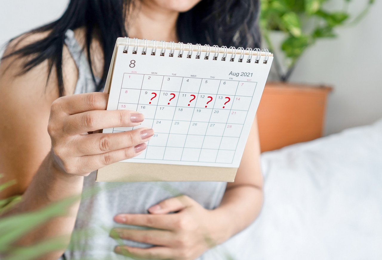 Woman holds a calendar with question marks on dates.
